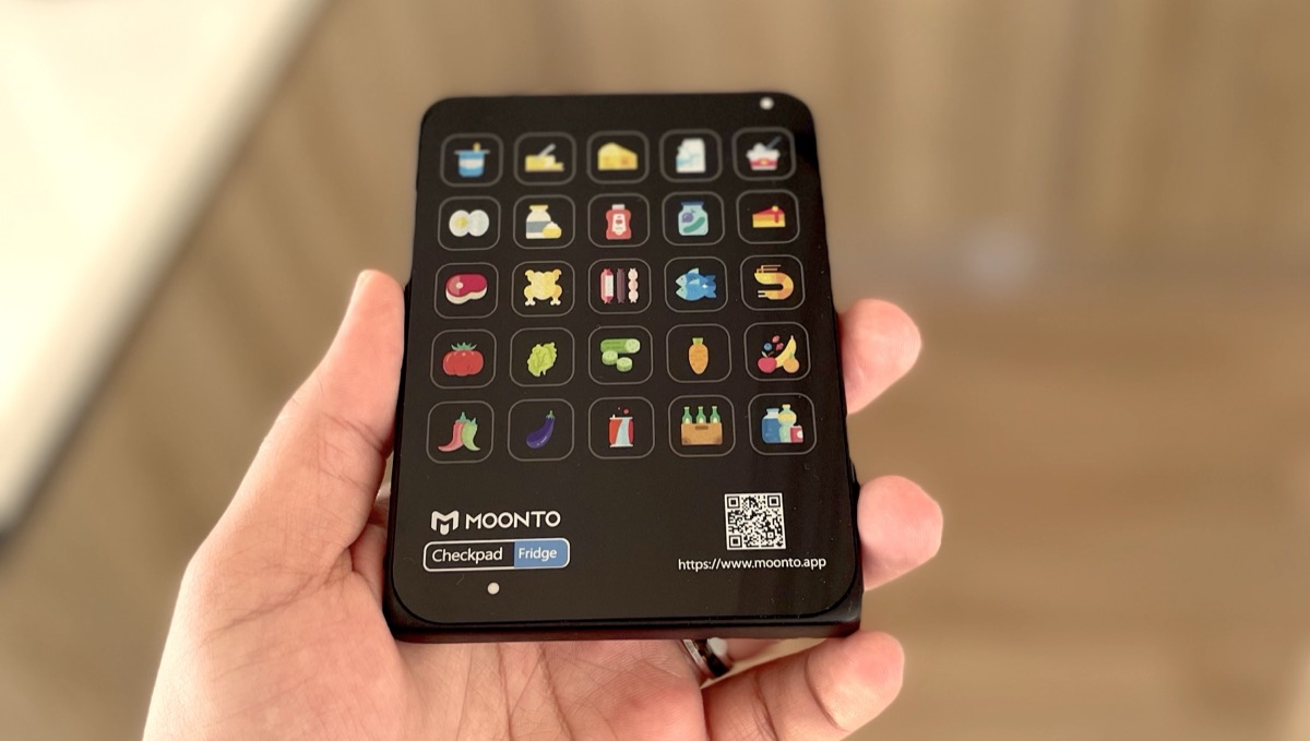 A hand pressing a button on the Checkpad wall pad